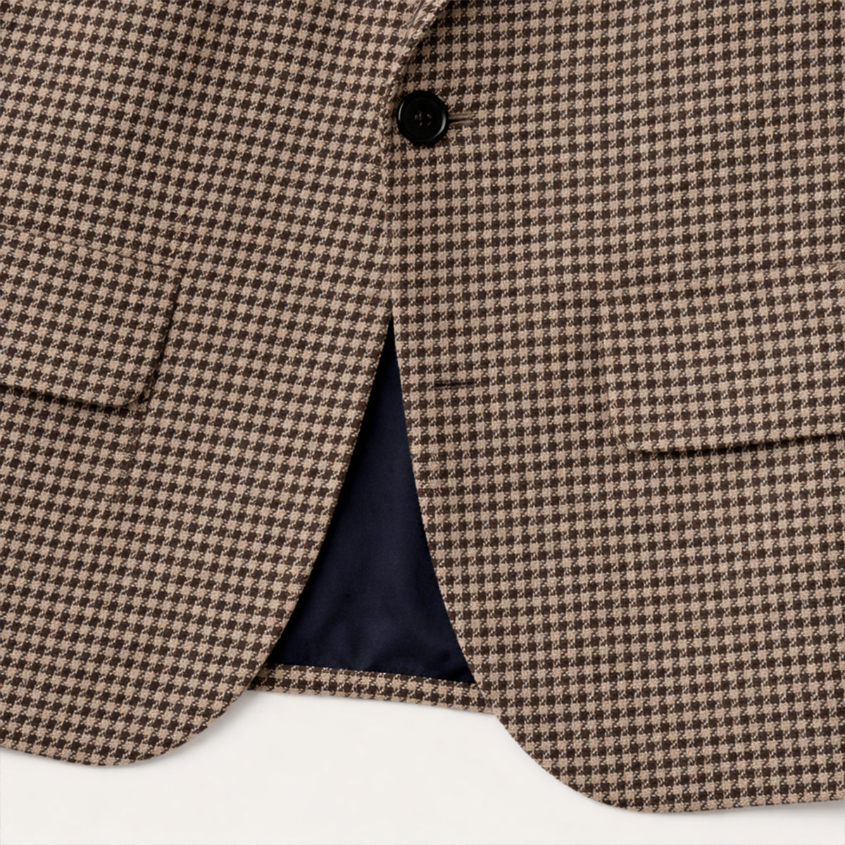 Brown houndstooth tweed blazer close-up of front button, lapel opening, and pocket welt