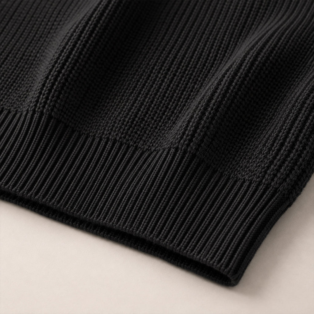 Black ribbed knit sweater hem with textured stitch pattern.
