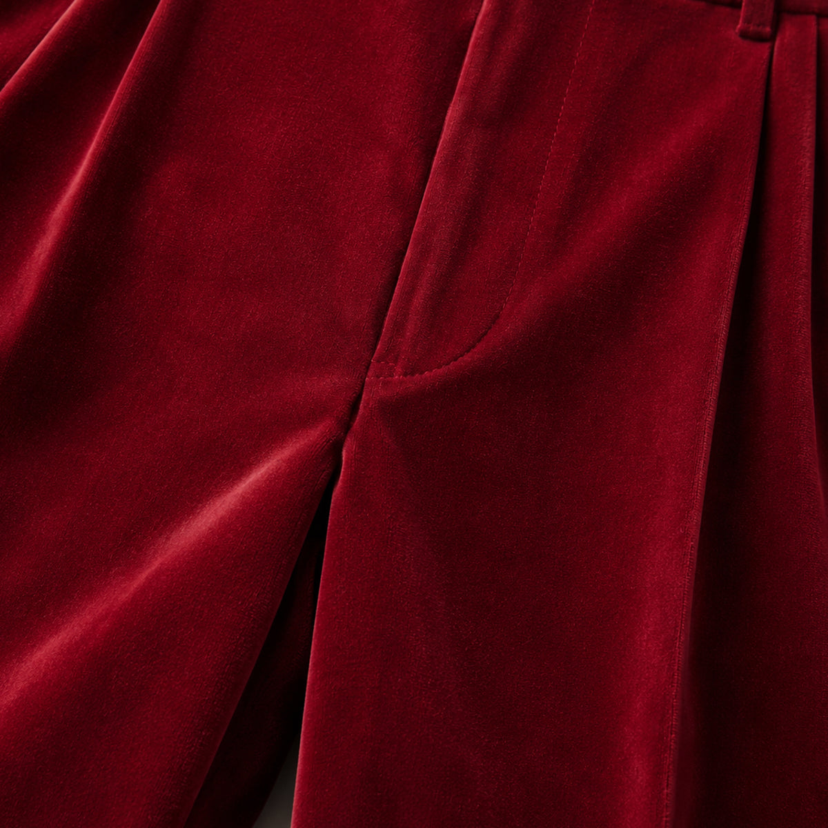 Burgundy velvet straight-fit pants close-up of front seam and side pocket