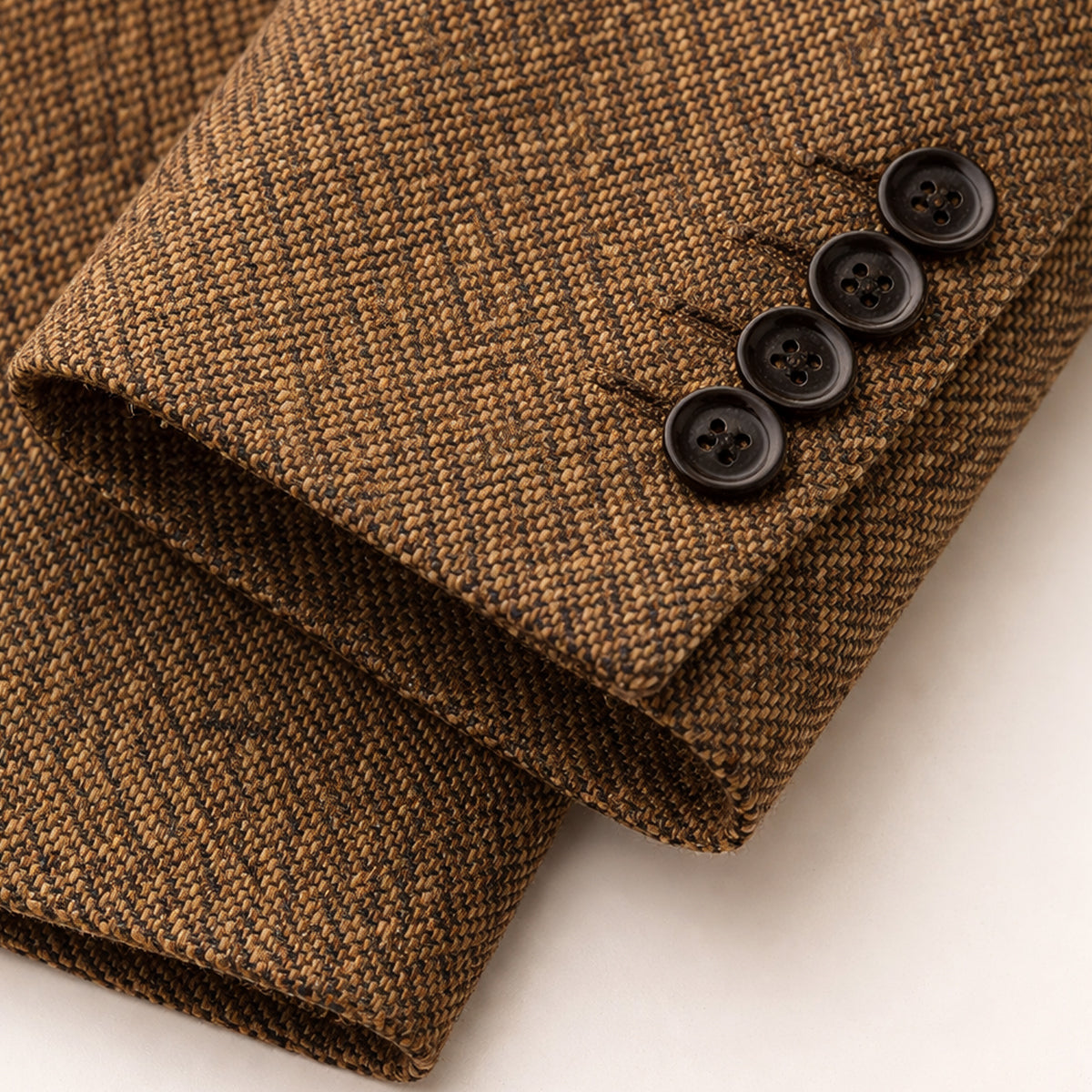 Brown herringbone tweed blazer cuff with dark four-button sleeve detail.