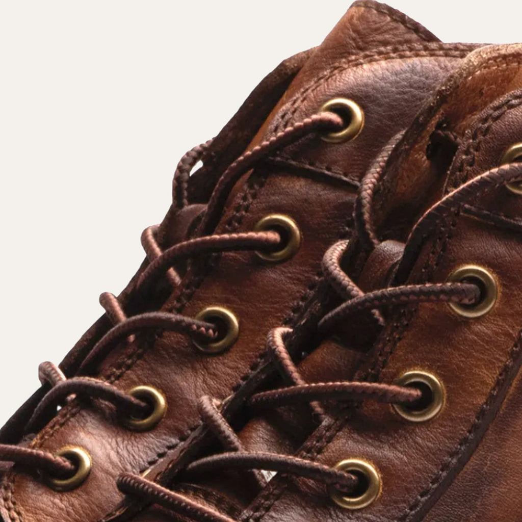 Close-up of men's brown lace-up ankle boots with metal eyelets and stitched seams
