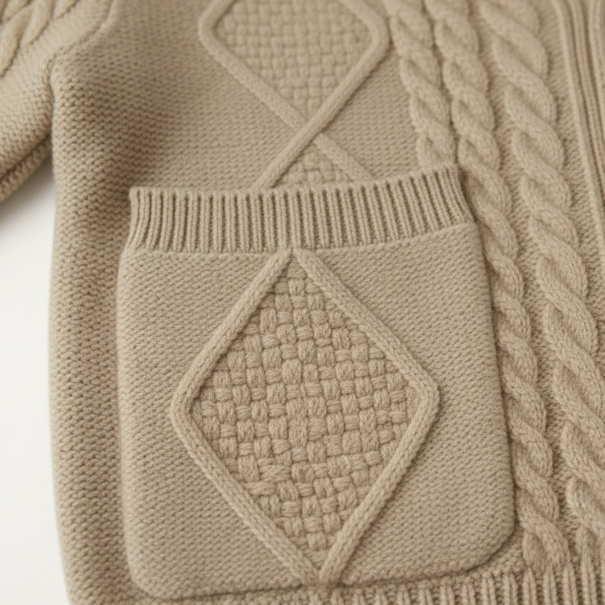 Beige cashmere cardigan close-up of cable patch, ribbed trim, and pocket panel