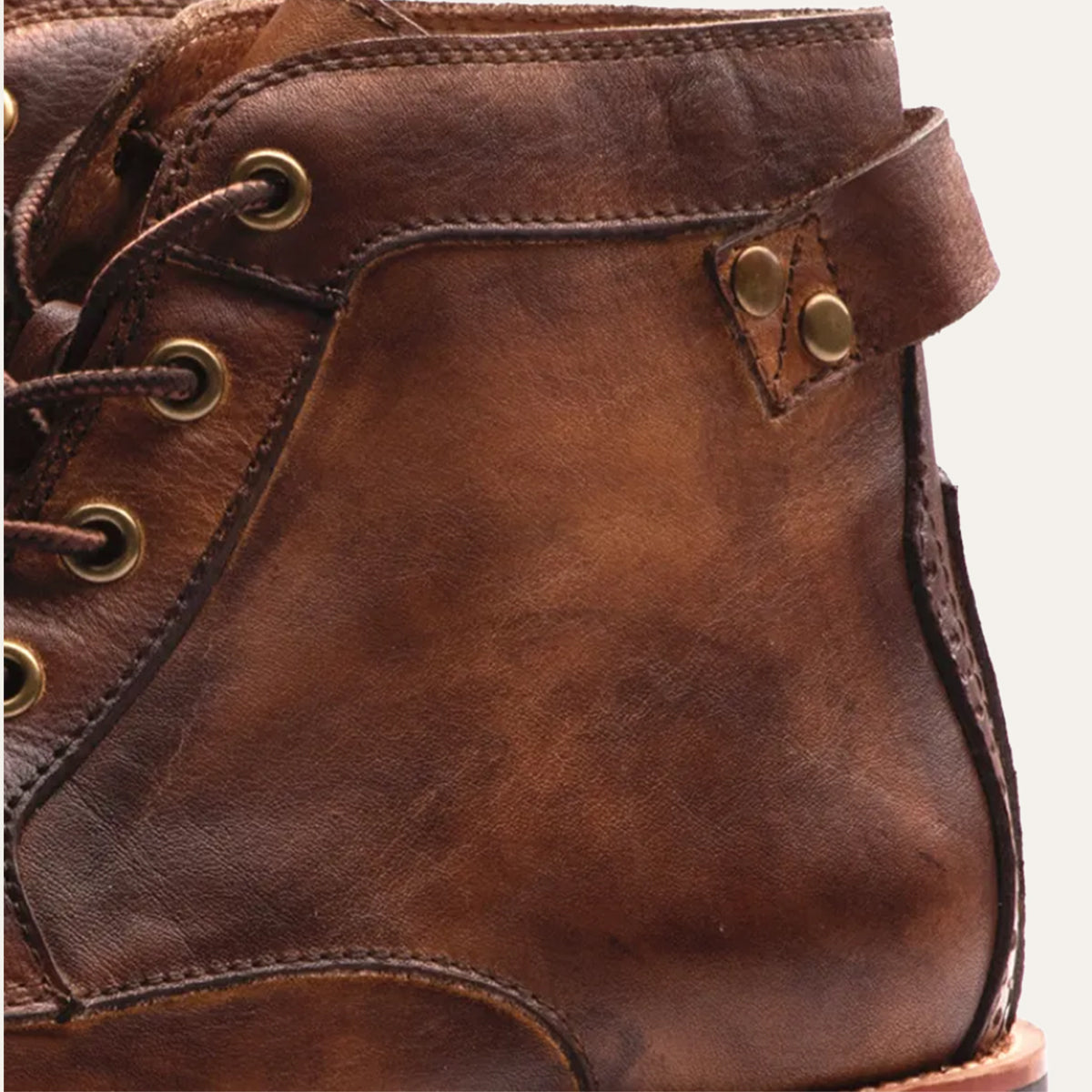 Close-up of men's brown lace-up ankle boots with padded collar and metal eyelets
