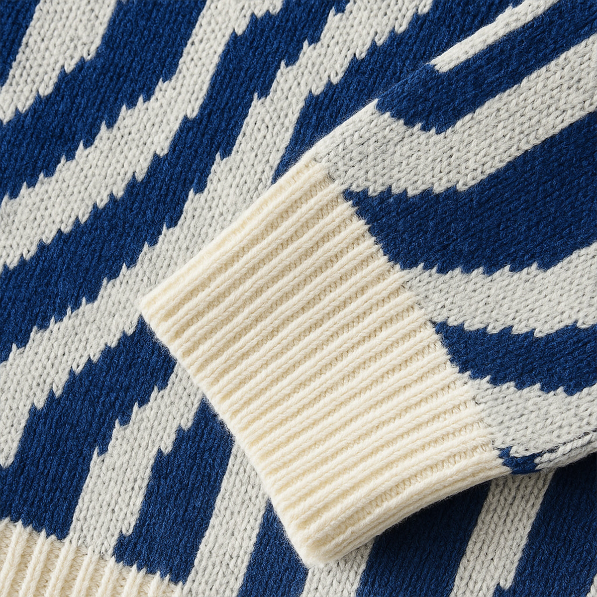 Close-up: cream ribbed cuff on blue-and-cream jacquard knit sweater with swirl lines