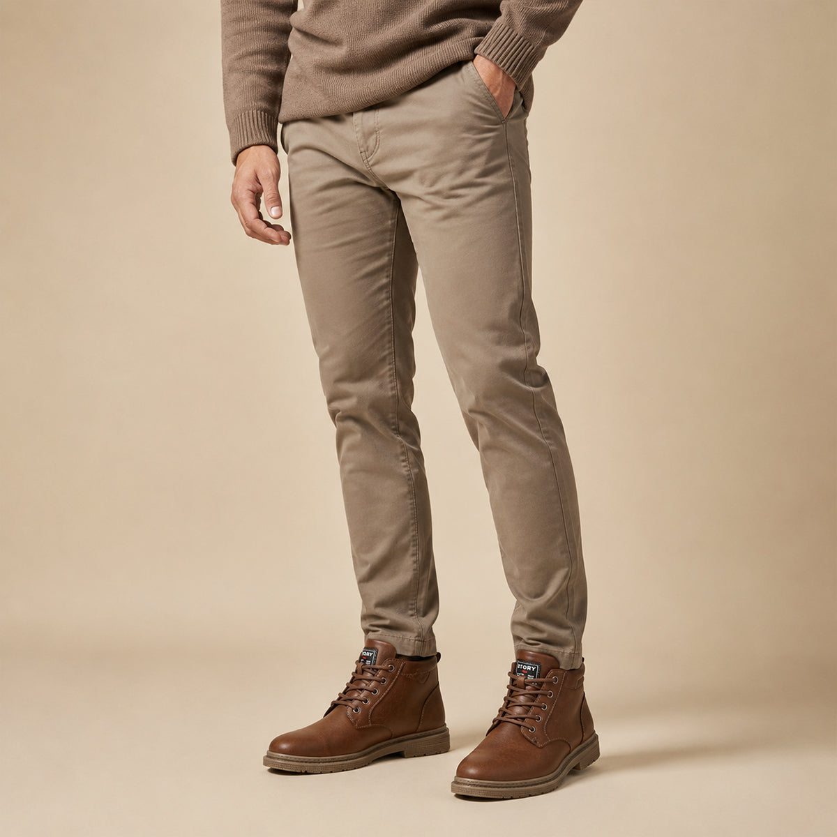 Brown leather ankle boots with lace-up front and rubber outsole, worn with tan pants