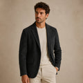 Men's black blazer with notched lapel and flap pockets, worn open at front