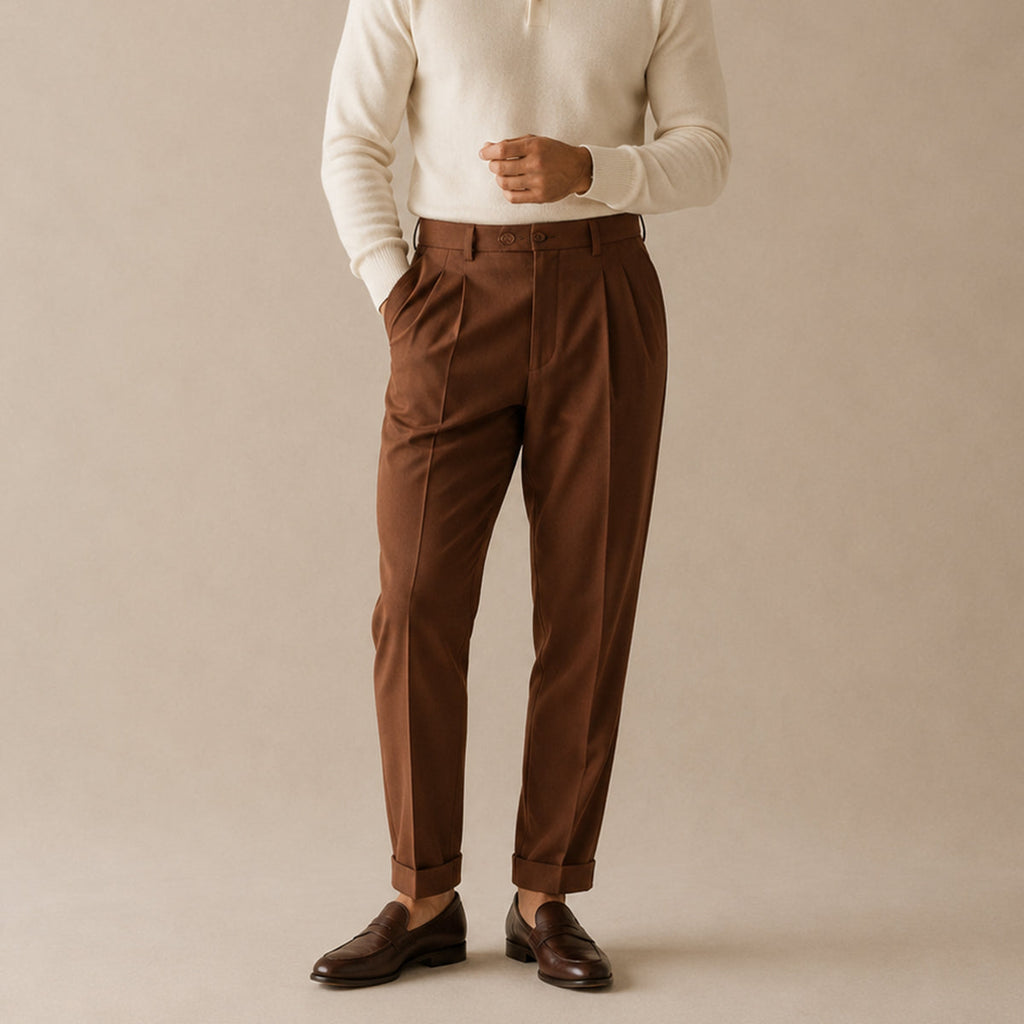 Brown high-waist double-pleated trousers on model, tailored fit, cuffed hem.