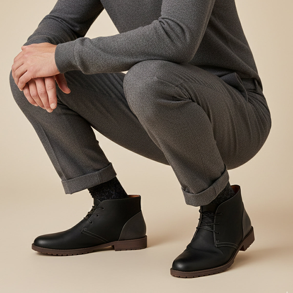Men's black lace-up ankle boots with textured sole worn with gray suit trousers